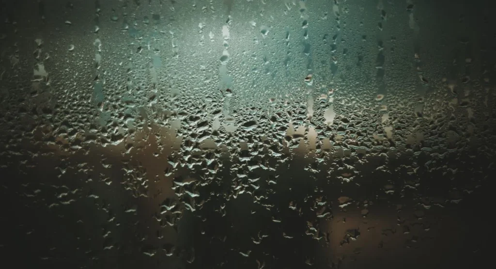 Beschlagenes Fenster mit Wassertropfen im Wintermorgen Innenraum