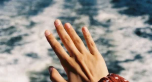 Was tun, wenn sekundenkleber auf der haut klebt? Hand mit Sekundenkleber an Fingern unter fließendem warmem Wasser