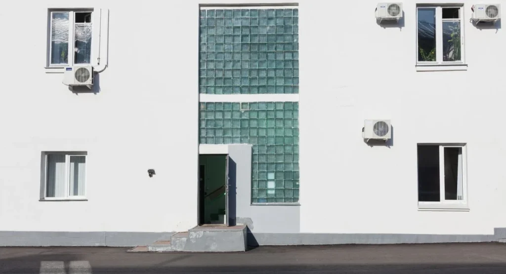 Techniker installiert Luft-Wasser-Wärmepumpe an Hausfassade im Winter