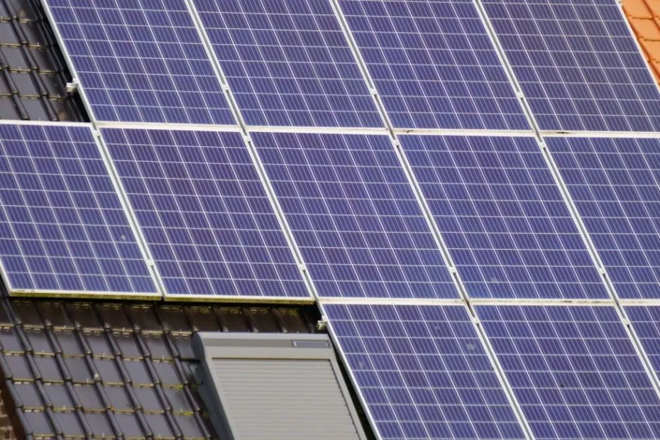 Techniker montiert Solarmodule auf Schrägdach mit Stromspeicher im Hintergrund
